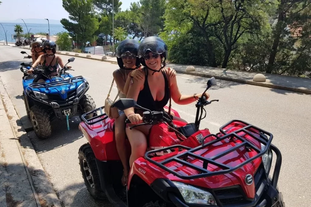 Two friends smiling on red and blue quad bikes on Brač